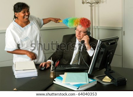 Funny cleaning woman cleaning the office of the manager including his face