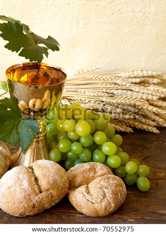 Grapes and holy bread next to a golden chalice with wine