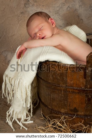 Vintage photo of a newborn baby of 18 days old sleeping in an antique bucket