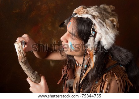 Portrait of an Indian in traditional costume wearing eagle feathers, coyote fur and beads