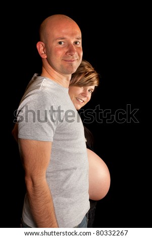 Happy couple showing the pregnant belly of his wife