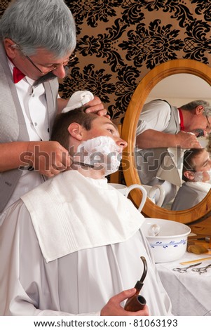 Antique barber shaving a customer the old-fashioned way