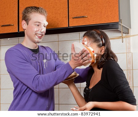 Young man putting a cream pie in his girlfriend\'s face