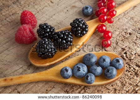 Autumn berries and wooden spoons on an old board