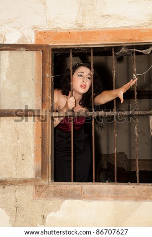 Pretty woman behind bars of a grungy derelict building