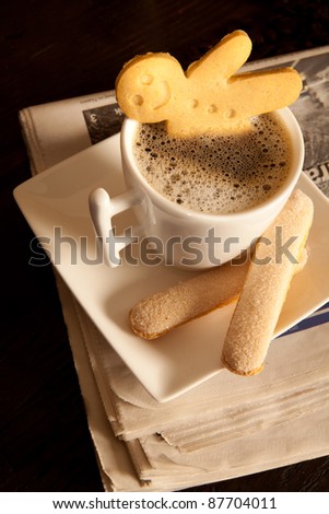 Gingerbread men cookie biscuits with hot coffee on folded newspapers