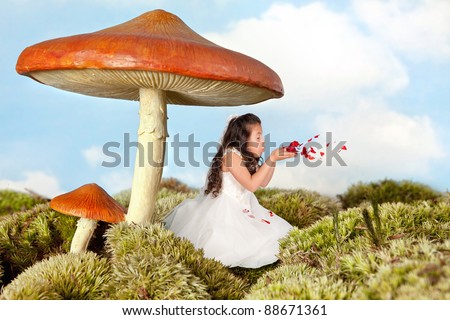 Little fairy girl blowing rose petals under a toadstool umbrella