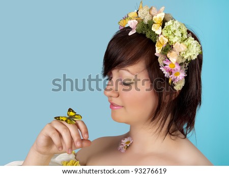 Springtime woman with butterfly and flower hair holding a butterfly