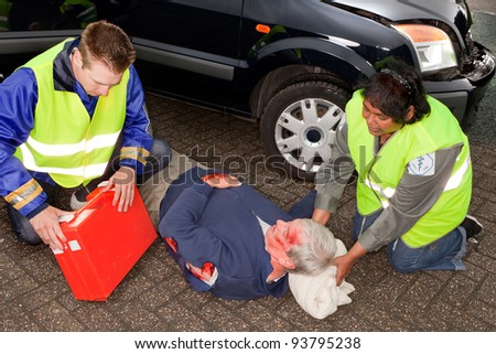 Car crash victim being helped by paramedics (the sleeve badges have been replaced by a non existing logo)