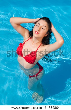 Bathing beautiful woman posing in her bikini in the swimming-pool
