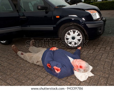 Dead or unconscious man lying next to a wrecked car