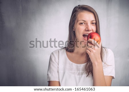 Pretty young woman biting into a fresh red apple