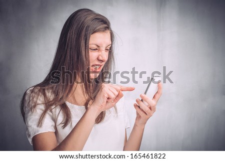 Angry young woman reading a text message on her cell phone
