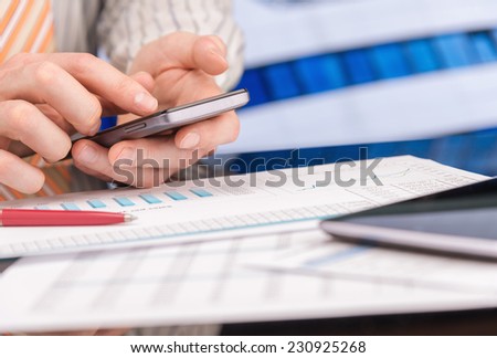 Man working with papers, charts, and smartphone in office