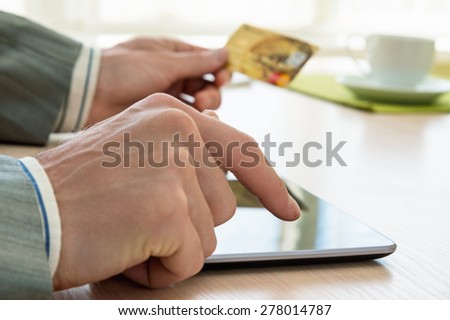 Businessman with credit card using tablet pc for internet shopping