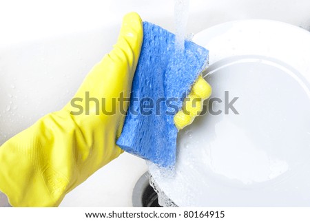 Washing a white plate with a sponge and rubber gloves
