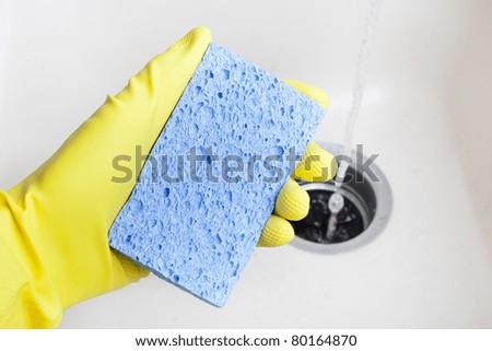 Washing a white plate with a sponge and rubber gloves