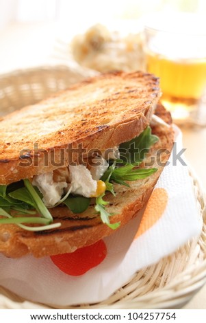 Chicken sandwich on bread basket with iced tea