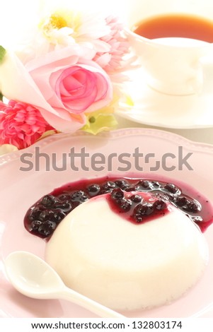 italian food, panna cotta and blueberry sauce on pink dish with english tea