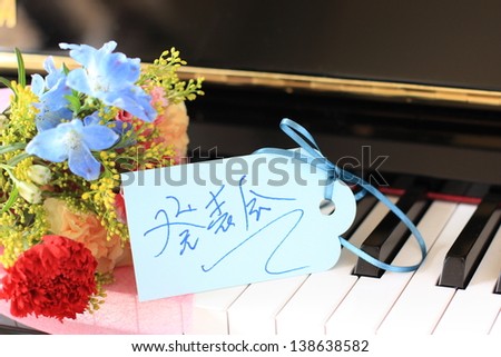 flower bouquet on piano key board with hand written piano recital card