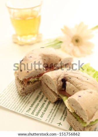 blue berry bagel with smoked salmon sandwich with iced tea and flower on background