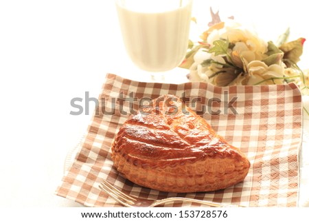 home bakery meat pie on paper napkin with flower and glass of milk on background,