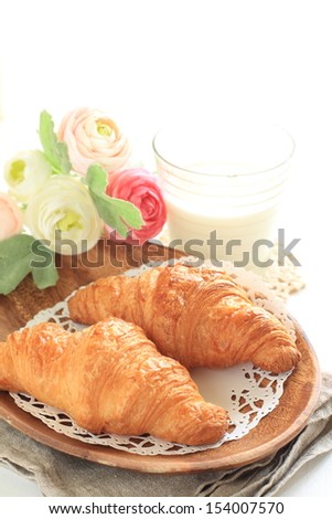 french bread, croissant on wooden dish with flower and milk on background for gourmet breakfast