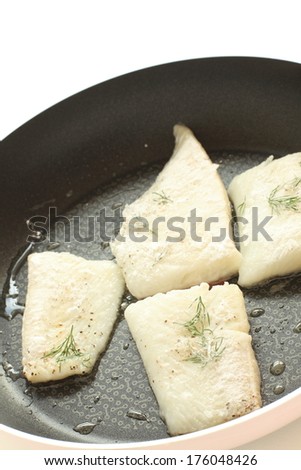 cooking of dill weed and flat fish on frying pan