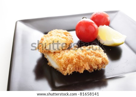 Japanese cuisine, squid cutlet with lemon and cherry tomato on square black plate