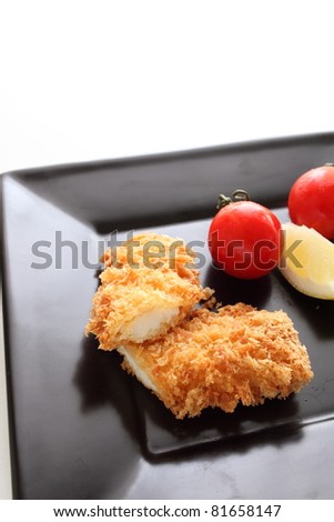 Japanese cuisine, squid cutlet with lemon and cherry tomato on square black plate