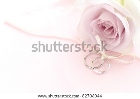 stock photo pair of wedding rings with pastel purple rose for background 
