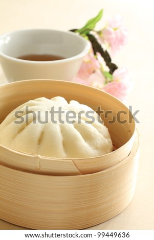 Chinese steamed dumpling, meat bun on bamboo steamer with hot tea