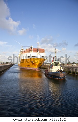 Huge container ship with tug boat in lock
