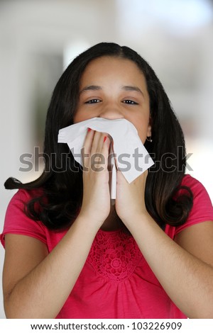 Teenage girl blowing her nose with tissue