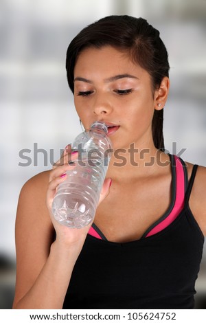 Teen girl drinking water at the gym
