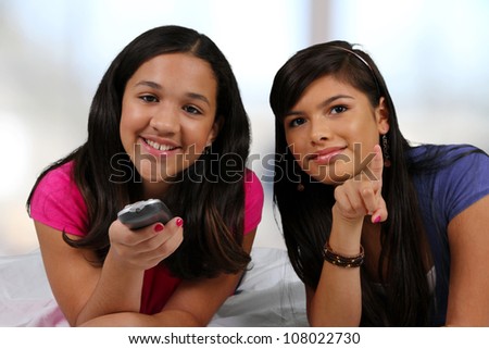 Teenage girl laying in her bed with her friend watching TV