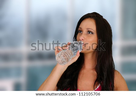 Young womanl drinking water at the gym