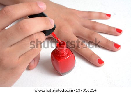 Girl with her nails painted a red color with a clear coat