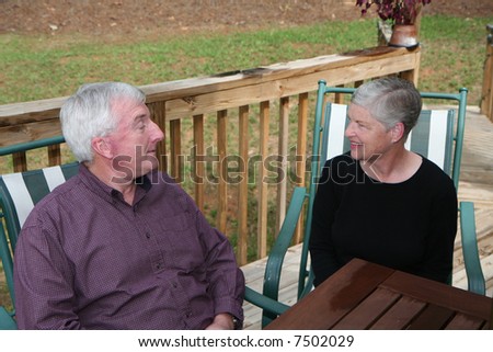 Happy Senior Couple smiling outside at table