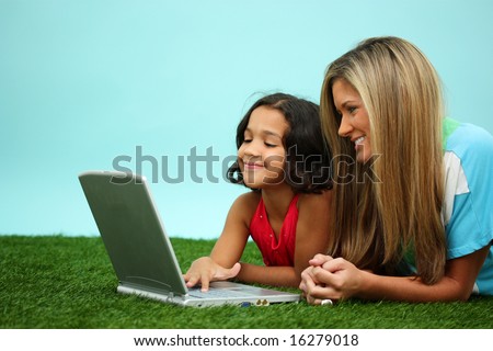 Family Laying Together Outside In The Grass With Computer