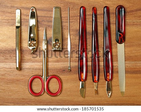 Personal hygiene items on wood background. Metal tweezers, hair clip, nail clippers, and scissors