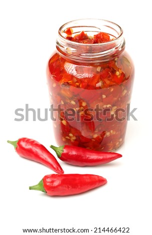 Fresh red chilly and bottled chili sauce over white background