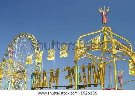 rollercoaster on a carnival area with a big wheel in the background