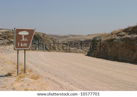 Road sign next to a namibian gravel road in the wilderness showing the distance to the next rest place