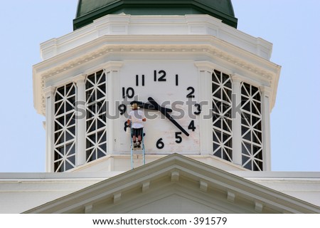 Man on ladder repairing clock on county court house building in Sylva, North Carolina