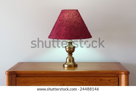 Energy saving halogen light in a lamp with a red shade on a dresser