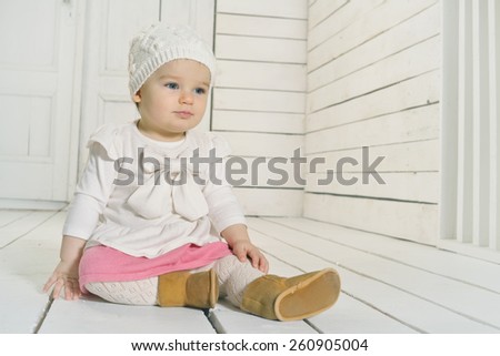 Cute baby girl sitting on the floor in a knitted hat.