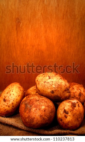 Raw Potatoes with soil on wooden box on gunny bag with wooden background