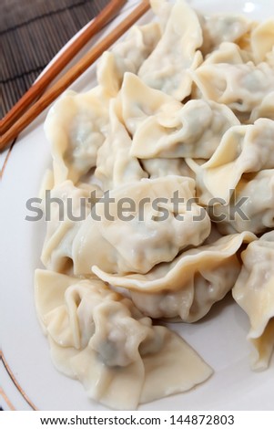 Plate of cooked chinese dumplings on bamboo mat