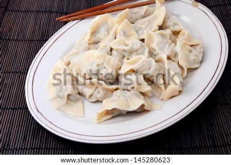Plate of cooked chinese dumplings on bamboo mat